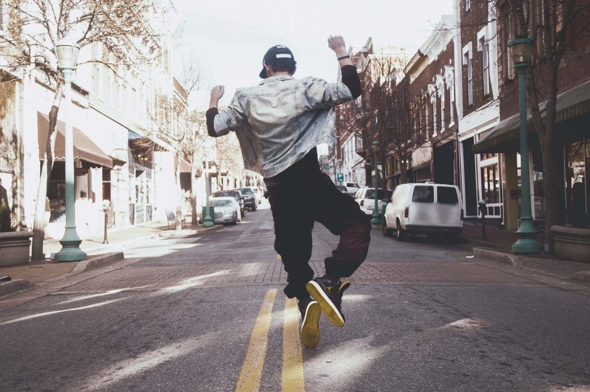 A man leaps mid-stride down the center line of a brick-lined main street.